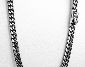 May include: A silver curb chain necklace with a clasp.