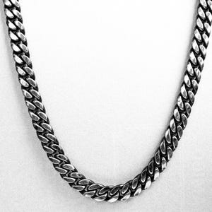 May include: A silver curb chain necklace with a thick, textured design.