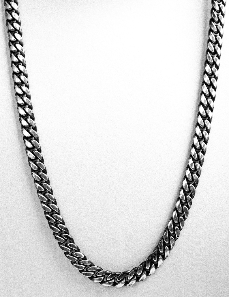 May include: A silver curb chain necklace with a classic design. The chain is made of metal and has a shiny finish.