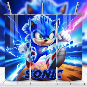 May include: A blue tumbler featuring Sonic the Hedgehog in a dynamic running pose. The design includes lightning bolts, a cityscape silhouette, and the word "SONIC" in a neon-style font. The tumbler has a silver straw.