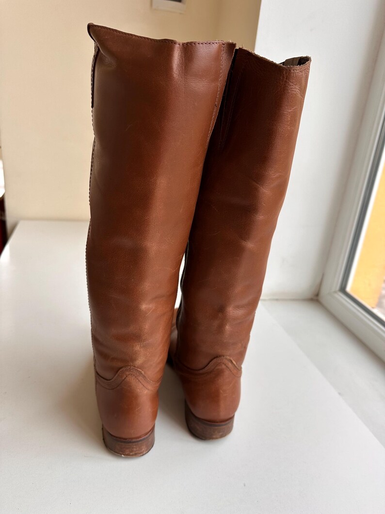 Pu&ograve; includere: Un paio di stivali alti in pelle marrone. Gli stivali hanno un design classico con una finitura liscia e lucida. I tacchi sono bassi e le suole sono di un marrone pi&ugrave; scuro. Gli stivali sembrano essere in buone condizioni.