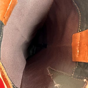 Pu&ograve; includere: Vista ravvicinata all'interno di uno stivale alto. Lo stivale presenta una combinazione di pelle marrone, nera e arancione. La fodera interna &egrave; in tessuto marrone tenue. Le cuciture bianche accentuano le cuciture.