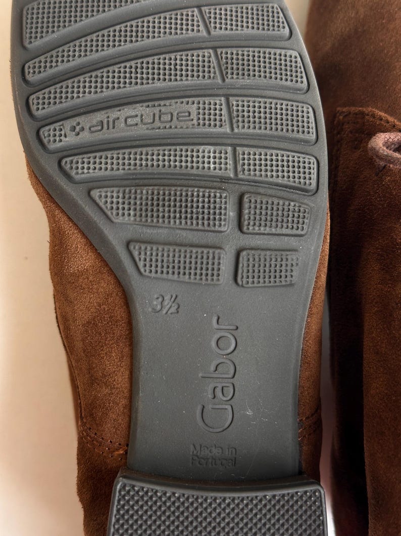 K&ouml;nnte beinhalten: Nahaufnahme der Sohle eines braunen Wildlederschuhs. Die dunkelgraue Sohle tr&auml;gt die Aufschrift "aircube" und "Gabor". Die Schuhgr&ouml;&szlig;e ist 3 1/2. Die Worte "Made in Portugal" sind ebenfalls zu sehen.