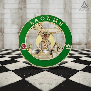 May include: A circular emblem with a green border and the letters "AAONMS". The emblem features a sword, crescent moon, star, pyramids, and a camel. The design is primarily gold and green, with accents of red and yellow.