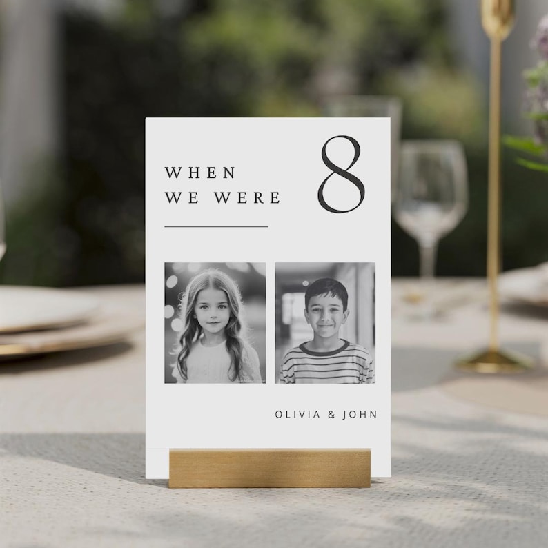 May include: Black and white photo table number card with the number 8, the text "WHEN WE WERE" and two photos of children. The text "OLIVIA & JOHN" is at the bottom of the card.
