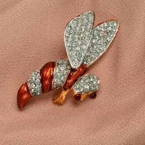 May include: A gold-tone bee brooch with red enamel and clear rhinestones.