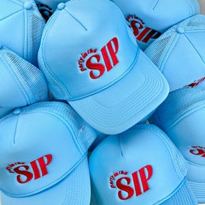 May include: A group of light blue trucker hats with a red embroidered logo that says "Party in the SIP".