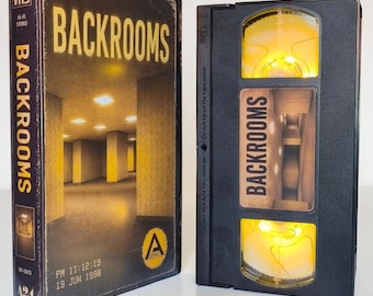 May include: A black VHS tape and its matching cardboard slipcase, both labeled Backrooms. The case features a yellow-lit, empty office hallway image, while the tape itself glows with a bright yellow light from within its central window.