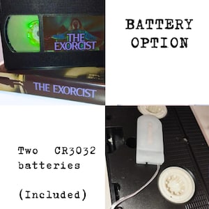 May include: A black VHS tape of "The Exorcist" movie. The tape has a green reel and a label with the movie title and imagery. The text "BATTERY OPTION" is displayed. Two CR3032 batteries are included.