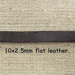 Può includere: Un primo piano di una striscia di cuoio marrone, larga 10 mm e spessa 2,5 mm. Il cuoio è piatto e liscio, con una leggera grana. 10x2.5mm cuoio piatto.