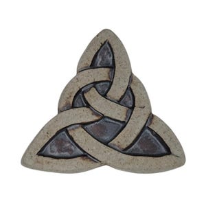 Op de afbeelding: Een Keltische knoop van keramiek, ook wel bekend als een Trinity-knoop, in een lichtbruine kleur met donkerbruine accenten. De knoop heeft de vorm van een driehoek.
