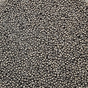 May include: A close-up shot of a large pile of small, metallic silver beads. The beads are densely packed together, creating a textured surface. The beads are round with a small hole in the center.