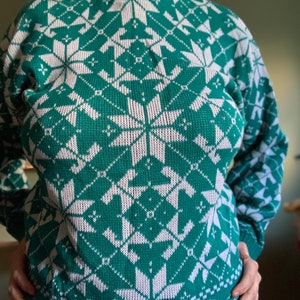 May include: A green and white knitted sweater with a snowflake pattern.