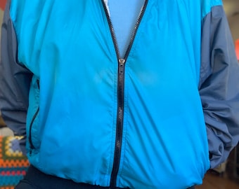 May include: A blue and gray windbreaker jacket with a black zipper and a Nike logo on the right side of the chest.