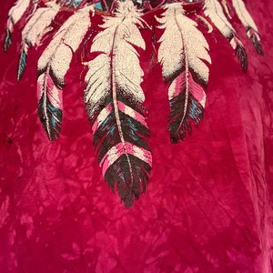 May include: A maroon tie-dye t-shirt with a Native American inspired design featuring a dreamcatcher with feathers.