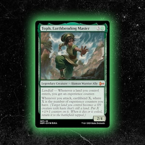 May include: A green Magic: The Gathering card featuring "Toph, Earthbending Master." The card depicts a character in green and tan clothing, set against a mountainous backdrop. The card has a power/toughness of 2/4.