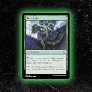 May include: A green Magic: The Gathering card titled "Burgeoning." The card features an illustration of a tree growing over a stone structure. Text on the card describes the enchantment's effect. The card has a green border and a black background.