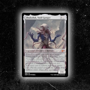 Puede incluir: Una carta de Magic: The Gathering con Zhulodok, Void Gorger. La carta tiene un borde negro e incluye el texto "Legendary Creature - Eldrazi". La ilustración representa una criatura azul y marrón con múltiples tentáculos. La fuerza y resistencia de la carta son 7/4.