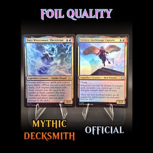 May include: Two Magic: The Gathering trading cards, "Dazz Wirecrosser: Electrician" and "Balmor, Battlemage Captain", displayed on clear stands. The cards have colorful artwork and text. The words "FOIL QUALITY", "MYTHIC DECKSMITH", and "OFFICIAL" are also visible.