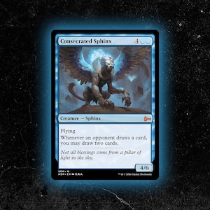 Puede incluir: Carta azul de Magic: The Gathering con un Esfinge Consagrada. La carta presenta una esfinge con alas azules y un aura brillante. El texto incluye "Esfinge Consagrada", "Criatura - Esfinge" y reglas del juego.