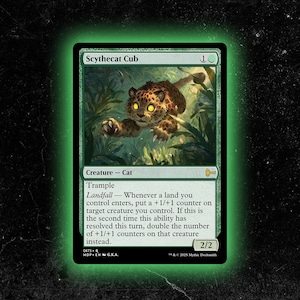 May include: A green Magic: The Gathering card featuring a Scythecat Cub, a creature cat with trample. The card art depicts a spotted feline in a jungle setting. The card's power and toughness are 2/2.
