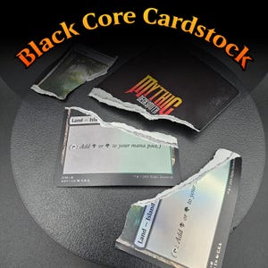 May include: Image of torn black cardstock with the text "Black Core Cardstock" in orange and yellow. Several torn pieces of cards are visible, including one with the "Mythic Decksmith" logo and others with "Land - Island" text.