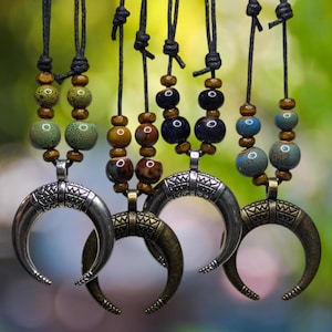 Puede incluir: Cuatro colgantes de plata en forma de media luna en cordones negros con cuentas de cerámica de colores. Las cuentas son verdes, azules y marrones.