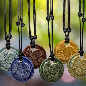 以下が含まれることがあります： らせん模様の丸いセラミックペンダントが付いたネックレスが7本。ペンダントは、青、緑、茶色、黄色など、さまざまな色があります。