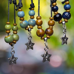 May include: Five necklaces with brown, blue, and green ceramic beads and silver star charms.