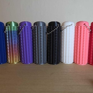 May include: A row of cylindrical, textured objects in various colors, including blue, green, purple, gray, black, white, pink, and red. Each has a chain attached. The objects have a spiky, ridged design.
