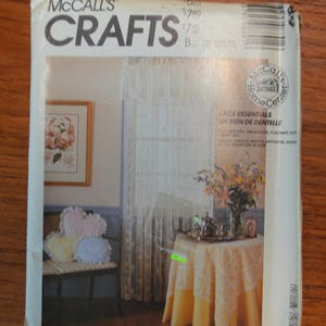 May include: A McCall's Crafts sewing pattern envelope for lace home decor items. The cover features a photograph of a room with lace curtains, a table covered in a lace cloth, and heart-shaped pillows. Text includes McCall's Crafts and Lace Essentials.
