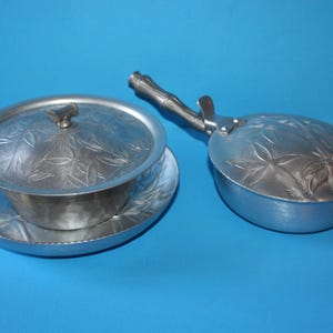 May include: A silver aluminium serving set with a lidded dish and a separate serving pan. Both pieces feature a floral design.