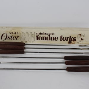 May include: A set of six Oster stainless steel fondue forks with dark brown wooden handles and colored tips in yellow, blue, red, and green. The forks are presented in a rectangular cardboard box labeled set of 6 stainless steel fondue forks.