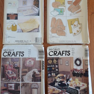 May include: Four vintage sewing pattern envelopes from Kwik Sew and McCall's Crafts. The Kwik Sew patterns 976 and 832 feature illustrations of baby bedding, bibs, and kitchen linens. The McCall's Crafts patterns 4666 and 4668 show home decor projects.