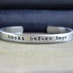 May include: A silver bracelet with the words "books before boys" engraved on it.