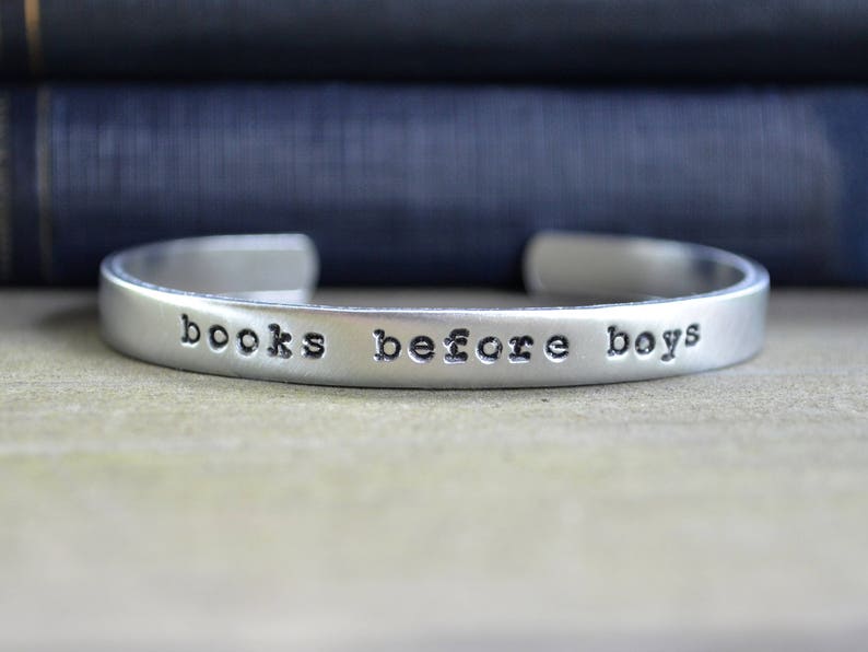 May include: A silver bracelet with the words "books before boys" engraved on it.