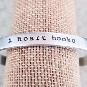 May include: A silver bracelet with the words "i heart books" engraved on it.