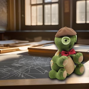 May include: A crocheted green turtle wearing a brown hat and a red bow tie. The turtle is sitting on a black surface with white lines.