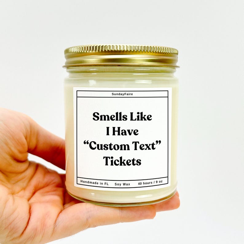 May include: A glass jar candle with a gold lid and a white label. The label reads "Sunday Faire", "Smells Like I Have "Custom Text" Tickets", "Handmade in FL", "Soy Wax", and "40 hours / 9 oz".