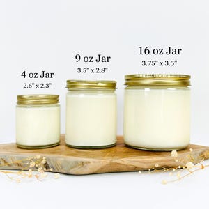 May include: Four glass candle jars with gold lids on a wooden surface. The jars are labeled with their size and dimensions in inches: 4 oz (2.6" x 2.3"), 9 oz (3.5" x 2.8"), and 16 oz (3.75" x 3.5").