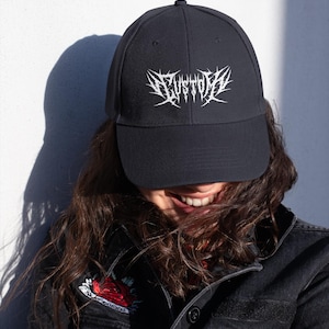 May include: A black baseball cap with a white embroidered design that says "CUSTOM" in a gothic font.