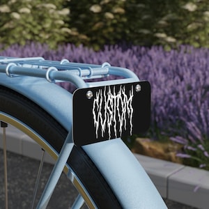 May include: A blue bicycle with a black metal number plate that says "CUSTOM" in white metal lettering.