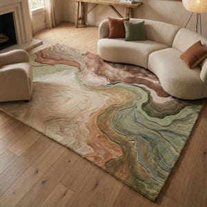May include: A large area rug with an abstract design in shades of brown, green, and beige. The rug has a flowing, marbled appearance, with curved lines and varying textures. It is placed on a wooden floor, with a curved sofa and armchair in the background.