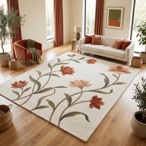 May include: A rectangular area rug featuring a cream-colored background with a large-scale floral pattern. The design includes stylized orange and peach-toned flowers with long, flowing green stems and leaves that extend across the surface.
