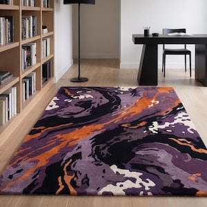 May include: A rectangular area rug featuring an abstract, swirling pattern in shades of deep purple, black, bright orange, and off-white. The design consists of fluid, organic shapes that flow across the surface, creating a bold, high-contrast visual.