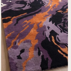 May include: A rectangular area rug featuring an abstract, swirling pattern of deep black, vibrant orange, and multiple shades of purple. The design consists of fluid, organic shapes that flow across the surface, creating a high-contrast visual effect.