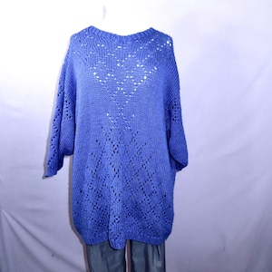 May include: A blue knit sweater with a round neckline and three-quarter sleeves. The sweater features a decorative openwork pattern on the front. The garment is displayed on a mannequin against a white background.