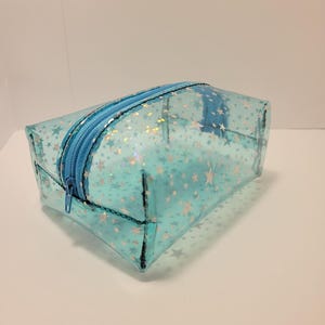 Puede incluir: Una bolsa de plástico transparente azul claro con cremallera y un patrón de estrellas blancas.