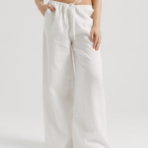 K&ouml;nnte beinhalten: Wei&szlig;e Leinenhose mit Kordelzug. Die Hose ist weit geschnitten und flie&szlig;end.
