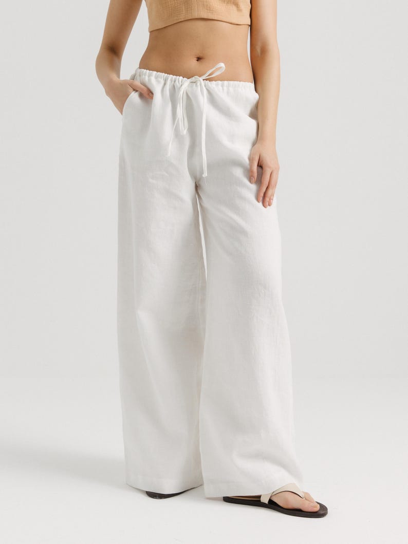 K&ouml;nnte beinhalten: Wei&szlig;e Leinenhose mit Kordelzug. Die Hose ist weit geschnitten und flie&szlig;end.